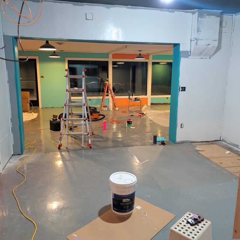 Inside the Mad Lab studio during build-out: ladders, paint supplies, and a bright pink door