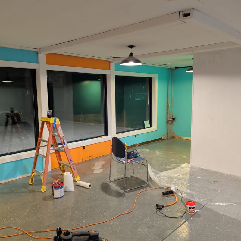 Mad Lab studio interior under renovation: teal and orange walls, industrial windows, and tools